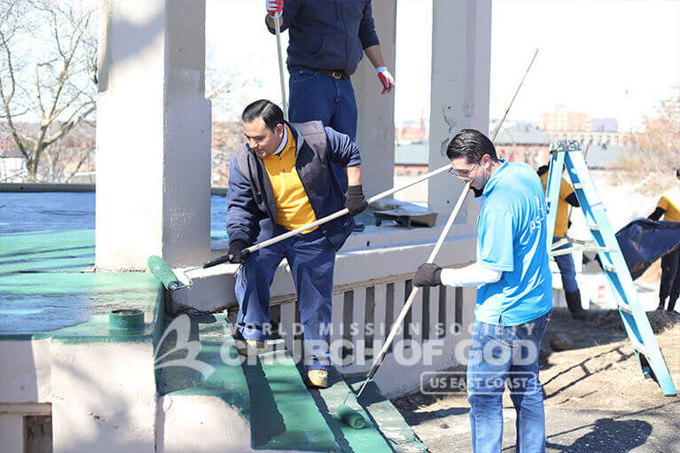ASEZ volunteers painting over decrepit stairs of a gazebo at Roberto Clemente Park.