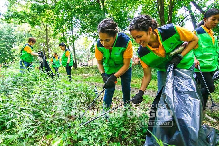 Two ASEZ WAO volunteers working together to pick up trash at the Heritage Trail.