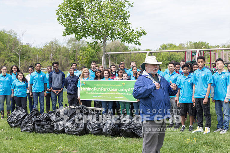 Parks and Recreation official speaking on the good deeds of ASEZ student volunteers after the Herring Run Park cleanup.