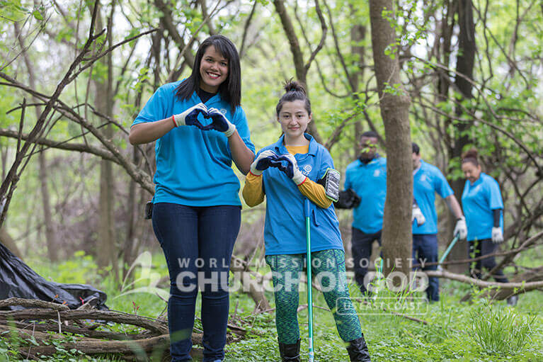 ASEZ volunteers making hearts with their hands as they clean up Herring Run Park with love.